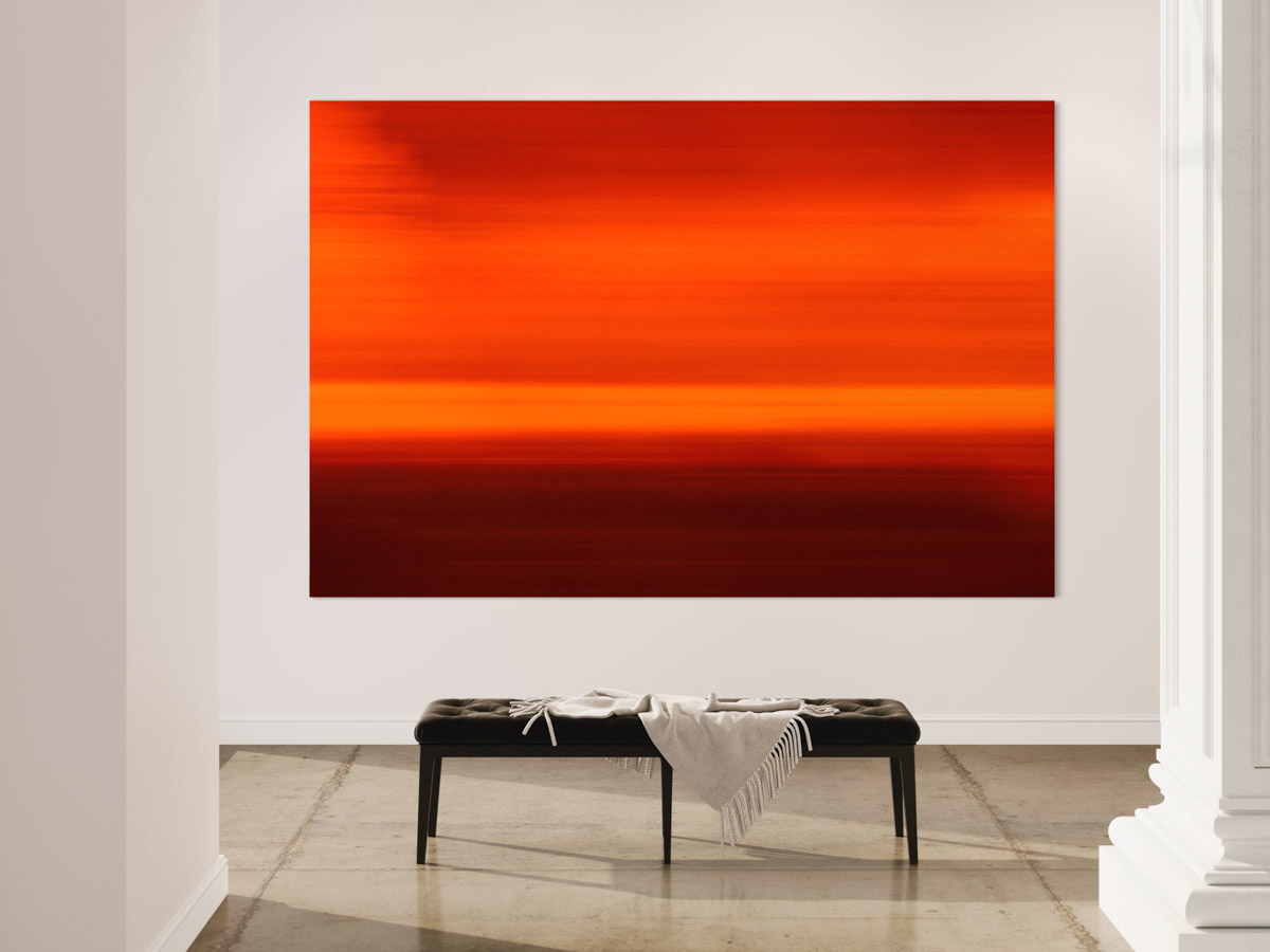 A large painting of an orange sky in the middle of a room.