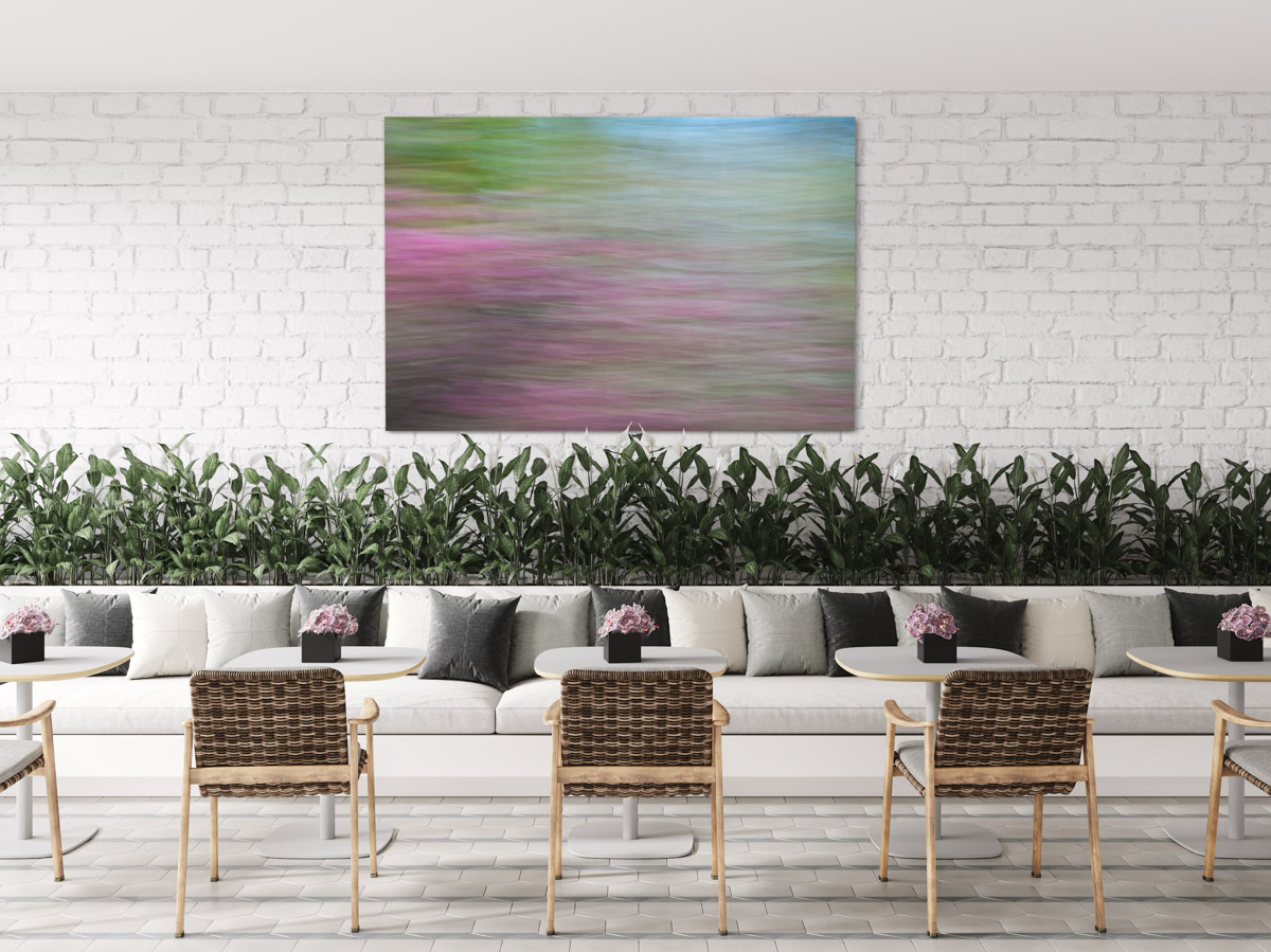 A painting of a green and pink field with chairs around it.