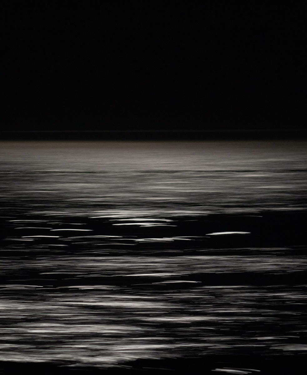 A black and white photo of the ocean at night.