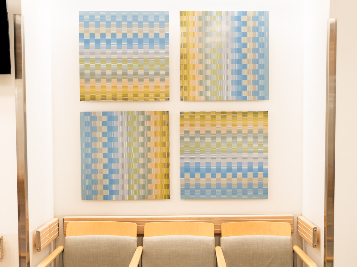 Four paintings hanging on a wall in a waiting room.